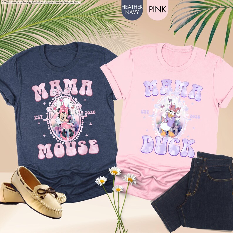 May include: Two t-shirts, one navy and one pink, with the text "MAMA" and character graphics. The navy shirt says "MOUSE" and the pink shirt says "DUCK". Both shirts have "EST 2026" and are paired with jeans and shoes.