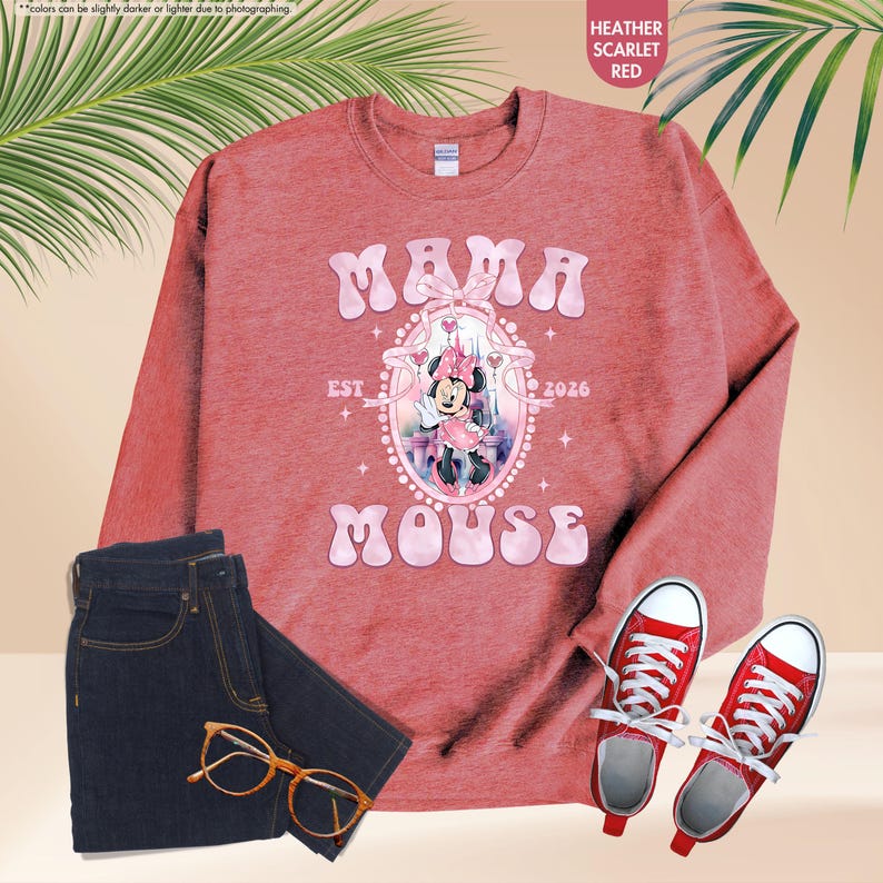 May include: A heather scarlet red sweatshirt with the words "MAMA MOUSE" and a Minnie Mouse graphic. The sweatshirt is paired with dark wash jeans, red sneakers, and eyeglasses.