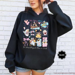 May include: Black hooded sweatshirt with a colorful graphic featuring Disney characters and the text "Walt Disney World" and "The Most Magical Place on Earth." The sweatshirt has a front pocket and a drawstring hood.