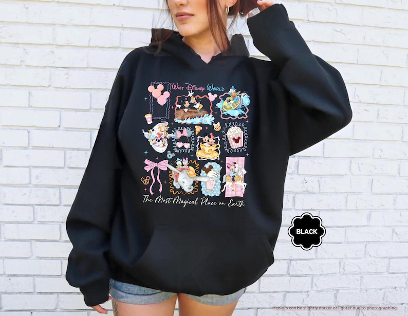 May include: Black hooded sweatshirt with a colorful graphic featuring Disney characters and the text "Walt Disney World" and "The Most Magical Place on Earth." The sweatshirt has a front pocket and a drawstring hood.