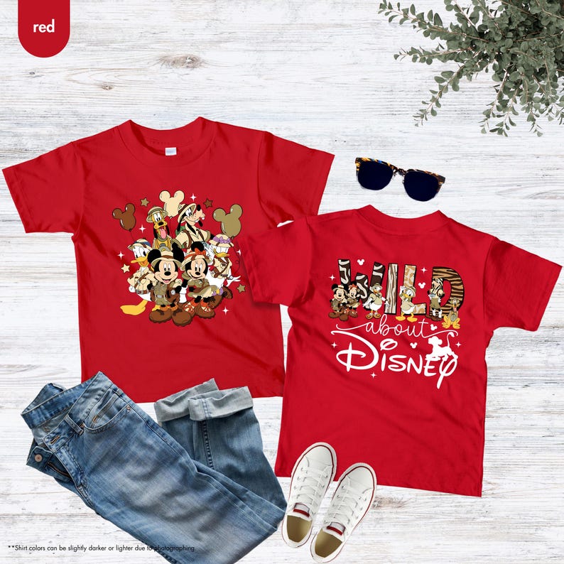 May include: Two red t-shirts featuring Disney characters. One shirt displays a group of characters, while the other says "Wild about Disney." Blue jeans, white sneakers, and sunglasses are also in the image.