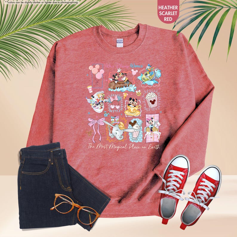 May include: Heather scarlet red sweatshirt with a colorful graphic of Disney characters and the text "The Most Magical Place on Earth." The image also includes dark blue jeans, red sneakers, and gold-rimmed glasses.