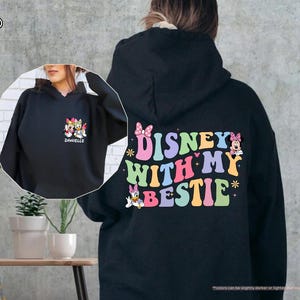 May include: Black hooded sweatshirt with a colorful graphic that says "Disney with my bestie" and features cartoon characters. The graphic also includes a pink bow, stars, and hearts.