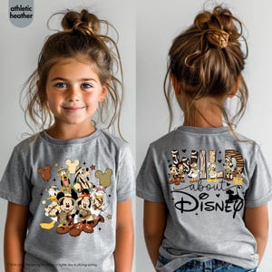 May include: A gray t-shirt featuring a Disney character design on the front and back. The front design includes Mickey and Minnie Mouse, Donald Duck, and Goofy. The back of the shirt says "Wild about Disney".
