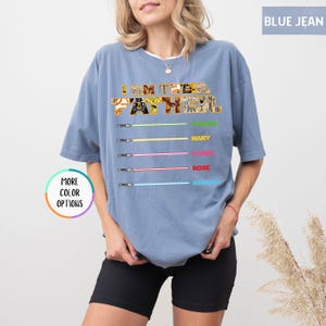 Puede incluir: Camiseta azul vaquero con el texto "I AM THE FATHER" en un dise&ntilde;o estampado. Debajo, gr&aacute;ficos de sables de luz con los nombres: Mary, Daniel, Rose y Robert. Un bot&oacute;n dice "MORE COLOR OPTIONS".