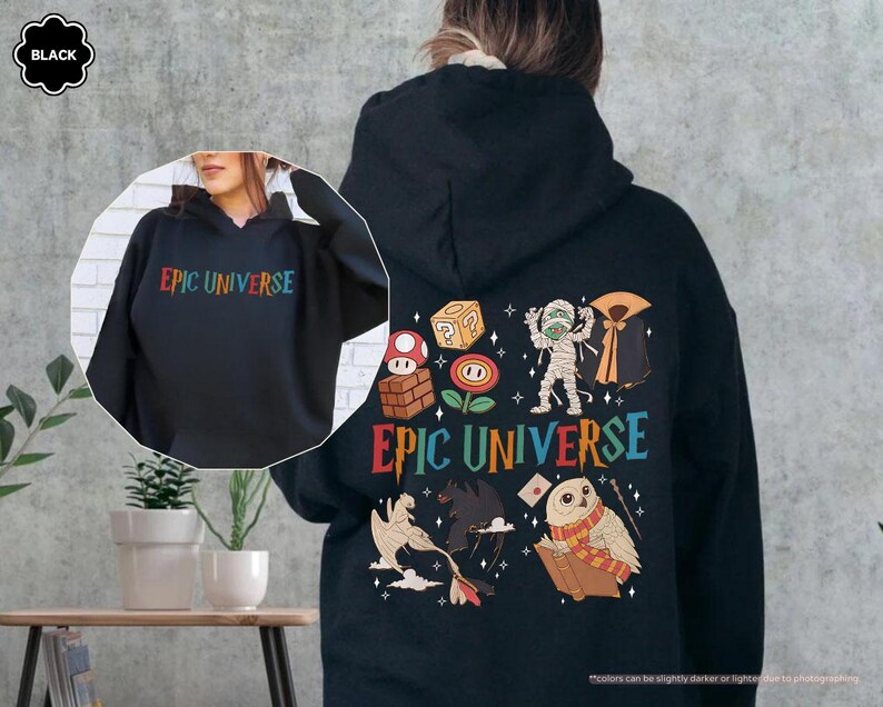 May include: Black hoodie with the text "EPIC UNIVERSE" in rainbow colors on the front and back. The back features colorful cartoon graphics of a mummy, owl, and other fantasy elements.