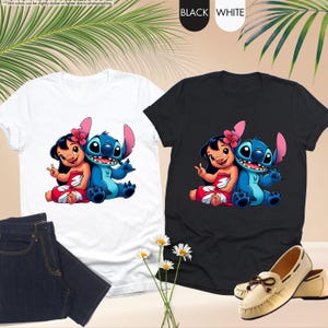 K&ouml;nnte beinhalten: Zwei T-Shirts, eines wei&szlig; und eines schwarz, mit einer Cartoon-Illustration von Lilo und Stitch. Das wei&szlig;e Shirt hat ein blaues und rotes Design, das schwarze Shirt hat ein &auml;hnliches Design. Die Shirts werden mit Jeans und Schuhen gezeigt.