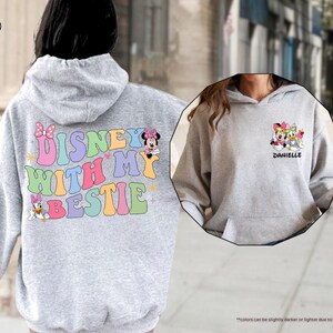 May include: A gray hoodie with a colorful "Disney with my bestie" graphic on the back and a smaller graphic of Disney characters on the front. The front graphic includes the text "Danielle".