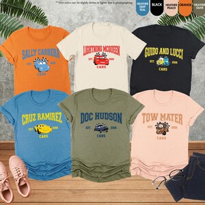 Puede incluir: Una colecci&oacute;n de camisetas con tem&aacute;tica de Cars en varios colores, incluyendo naranja, crema, negro, azul, verde oliva y melocot&oacute;n. Cada camiseta presenta el nombre y la imagen de un personaje, junto con el texto "Cars" y el a&ntilde;o "2006".