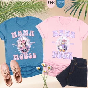 May include: Two t-shirts, one blue and one pink, with the text "MAMA" and character graphics. The blue shirt says "MOUSE" and the pink shirt says "DUCK". The image also shows a pair of pink sneakers and a pair of dark blue jeans.