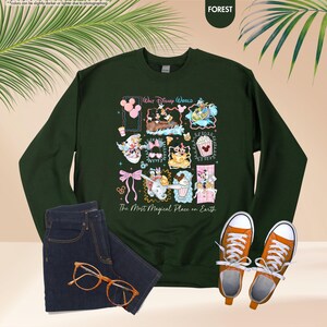 May include: Forest green sweatshirt featuring a colorful collage of Disney characters and icons. The text "Walt Disney World" and "The Most Magical Place on Earth" are also displayed. The sweatshirt is paired with blue jeans and orange sneakers.