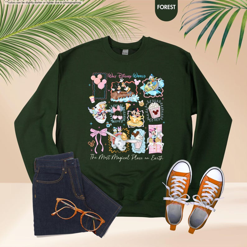 May include: Forest green sweatshirt featuring a colorful collage of Disney characters and icons. The text "Walt Disney World" and "The Most Magical Place on Earth" are also displayed. The sweatshirt is paired with blue jeans and orange sneakers.