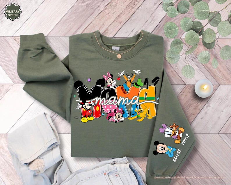 K&ouml;nnte beinhalten: Olivgr&uuml;nes Sweatshirt mit dem Wort "Mama" in farbenfrohen Disney-Buchstaben. Mit Micky, Minnie, Donald und Goofy. Der &Auml;rmel zeigt die Namen "Oliver" und "Emily" mit Micky und Daisy.