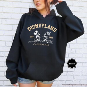 May include: A white ceramic mug with a black handle and the text "But First, Coffee" in a handwritten style. The mug is on a white surface. The mug is approximately 10 cm tall.