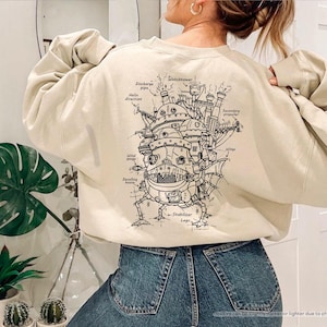 May include: A beige sweatshirt with a black and white illustration of a flying machine on the back. The illustration includes labels for different parts of the machine, such as "Watchtower", "Discharge pipe", and "Stabilizer Legs".