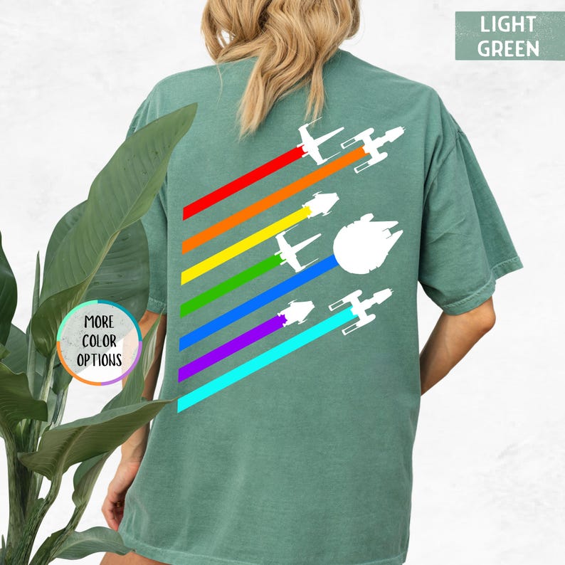 K&ouml;nnte beinhalten: Ein hellgr&uuml;nes T-Shirt mit einem Regenbogenmuster und wei&szlig;en Silhouetten von Star Wars Raumschiffen. Der Text "LIGHT GREEN" befindet sich in der oberen rechten Ecke des Bildes.