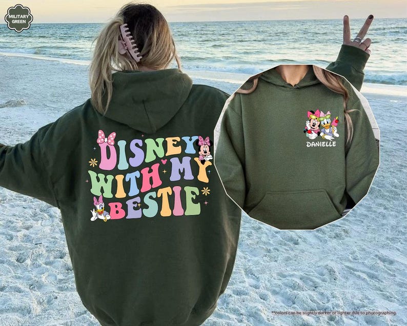 May include: A green hooded sweatshirt with the text "DISNEY WITH MY BESTIE" in colorful letters. The sweatshirt features a cartoon image of Minnie Mouse and Daisy Duck.