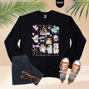 May include: Black long-sleeve sweatshirt with a colorful graphic featuring Disney characters and the text "Walt Disney World" and "The Most Magical Place on Earth." The sweatshirt is paired with blue jeans, orange sneakers, and glasses.