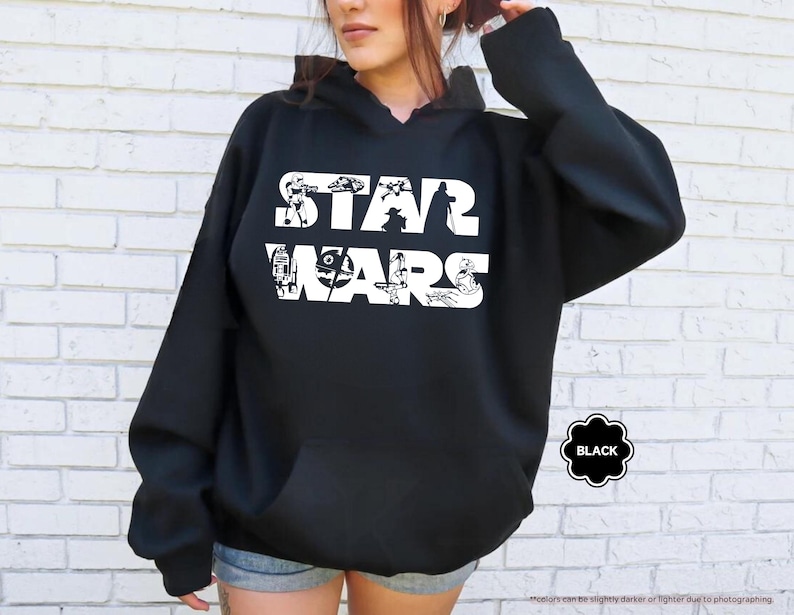 May include: Black hooded sweatshirt with the words "STAR WARS" in white, featuring character illustrations within the letters. The sweatshirt has a drawstring hood and a front pocket. The word "BLACK" is in a black and white circle.