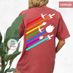 K&ouml;nnte beinhalten: Ein crimsonrotes T-Shirt mit einem Regenbogen-Design, das verschiedene Silhouetten von Star Wars-Raumschiffen zeigt. Der Text "CRIMSON" befindet sich in der oberen rechten Ecke des Bildes.