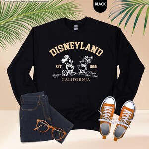 May include: A trio of cream-glazed ceramic mugs, each adorned with a hand-painted floral pattern in blue, green, and yellow. The mugs have a speckled finish and a classic, rounded design with a handle. Ideal for tea or coffee.