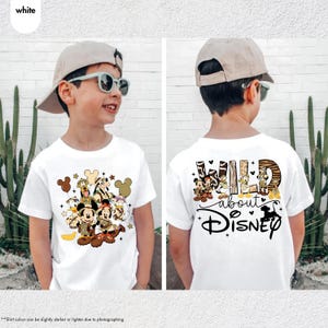 May include: White t-shirt featuring a Disney-themed design. The front displays Mickey and Minnie Mouse with other characters. The back of the shirt has the text "WILD about Disney" with character illustrations. The shirt is worn by a child.