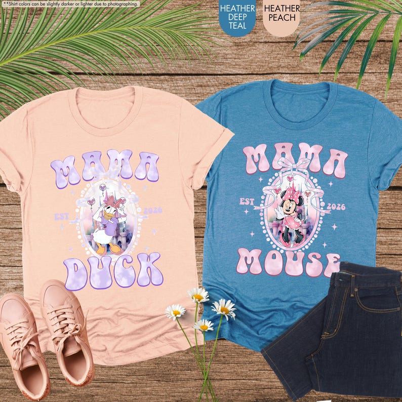 May include: Two t-shirts, one peach and one teal, with the word "Mama" in bubble letters. The peach shirt features Daisy Duck, and the teal shirt features Minnie Mouse. Both shirts have "Est 2026" printed on them. A pair of pink sneakers and a pair of blue jeans are also in the image.