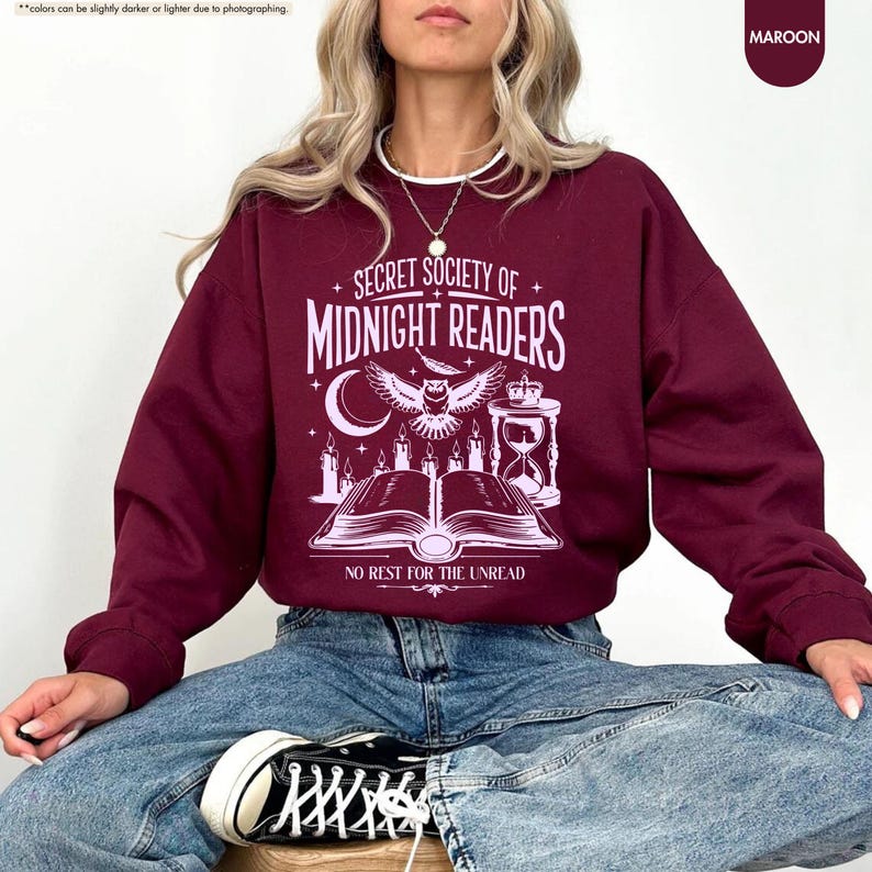 May include: Maroon sweatshirt with the text "SECRET SOCIETY OF MIDNIGHT READERS" and an owl graphic. The design includes a crescent moon, candles, an hourglass, and an open book. The phrase "NO REST FOR THE UNREAD" is below the book.