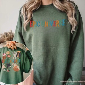 May include: A military green sweatshirt with the text "EPIC UNIVERSE" in colorful letters across the chest. The back of the sweatshirt features various cartoon characters and the same text. The sweatshirt is made of a soft material.