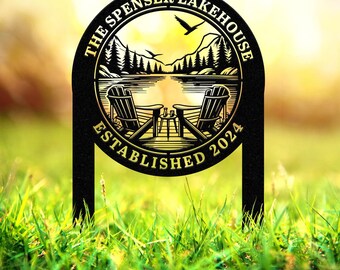 May include: Black metal yard sign with gold lettering that reads "The Spenser Lakehouse Established 2024". The sign features a lake scene with two chairs and a table.