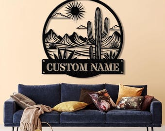 May include: Black metal wall art featuring a desert landscape with a cactus, mountains, and a sun. The art includes a personalized nameplate that reads "CUSTOM NAME".