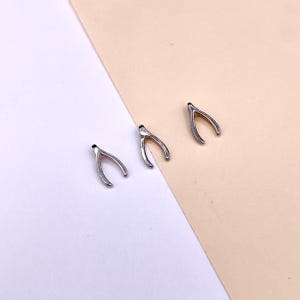 Peut inclure: Trois breloques en forme de fourchette à souhaits argentées, chacune avec une forme et une taille légèrement différentes.