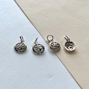 May include: Four silver charms with an Om symbol in the center. The charms are round and have a raised edge. The Om symbol is in a raised, stylized font.