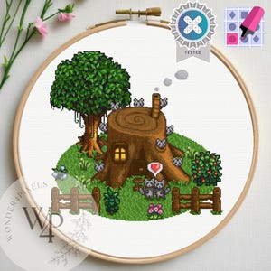 May include: A cross-stitch embroidery of a whimsical woodland scene. A tree stump home with a chimney, surrounded by a green landscape, a wooden fence, and a tree. Two gray raccoons are near a heart. The embroidery is in a wooden hoop.