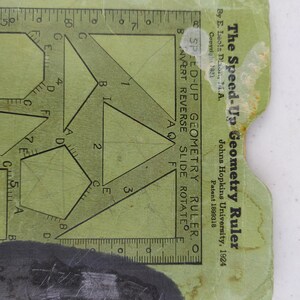 May include: Vintage Speed-Up Geometry Ruler, featuring geometric shapes and a ruler edge. The green cardstock tool includes text: "The Speed-Up Geometry Ruler" and "Johns Hopkins University, 1924". The ruler is designed for geometry calculations.
