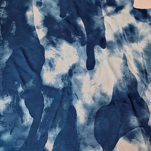 Pode incluir: Um pedaço de tecido com um padrão abstrato azul e branco. O design apresenta formas orgânicas fluidas em tons variados de azul sobre um fundo branco. O tecido parece ser uma fibra natural, possivelmente algodão ou linho.
