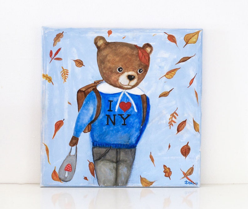 May include: An original painting of a brown bear wearing a blue sweater with "I NY" and a red heart. The bear is carrying a backpack and a bag with a mushroom design, with autumn leaves falling around it. The background is light blue.