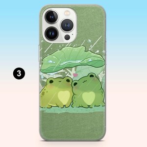 May include: Green phone case featuring a cartoon illustration of two frogs under a large leaf, with raindrops and a heart. The case has a textured green background and a clear border. The number "3" is in a black circle.