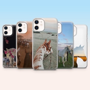 Può includere: Una collezione di cinque custodie per telefono con design a tema cavallo. Le custodie mostrano varie immagini, tra cui un cavallo con accenti floreali, cavalli in un campo e un cavallo bianco con un'imbracatura blu. Le custodie hanno una finitura trasparente e lucida.