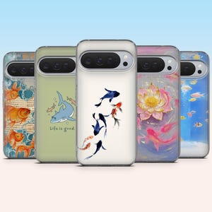 May include: A collection of phone cases with various aquatic designs. One case features goldfish, another a shark with the text "Life is good.", and others with koi fish, a lotus flower, and an underwater scene with fish.