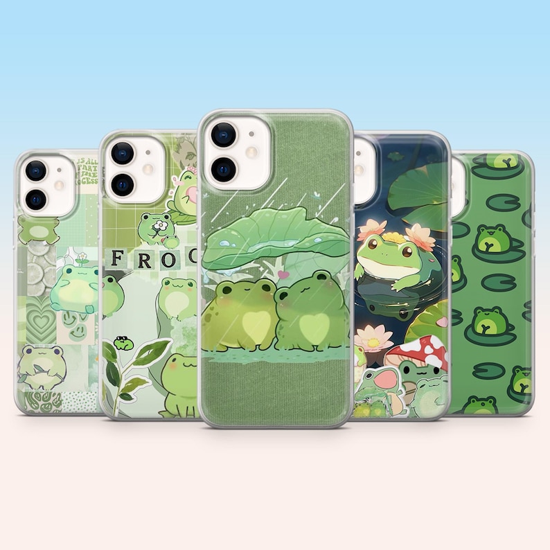 May include: A collection of five phone cases with various green frog designs. The cases feature illustrations of frogs, lily pads, and the word "FROG". The cases have a clear background with a gradient blue sky.