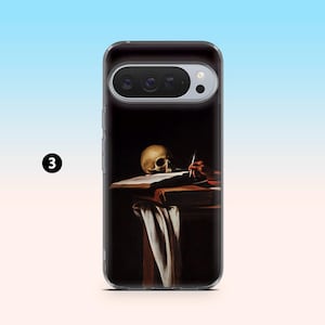 May include: A clear phone case featuring a painting of a skull, a hand holding a pen, and a book on a table. The artwork has a dark background with a white cloth draped over the table.