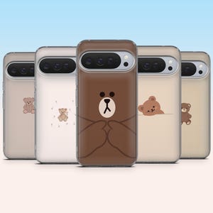 May include: Five smartphone cases arranged in a row, each featuring a unique brown bear illustration. The center case displays a large brown bear face, while the surrounding cases show smaller bear designs on clear or light-colored backgrounds.