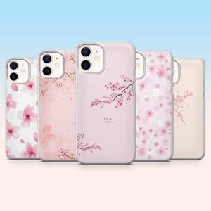 Peut inclure: Cinq coques de téléphone avec des motifs floraux. Les coques présentent des motifs de fleurs de cerisier roses sur un fond rose clair. Une coque comporte du texte japonais. Les coques sont en matériau transparent et protecteur.