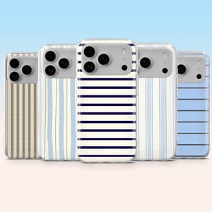 Puede incluir: Cinco fundas para teléfono con varios patrones de rayas. Las fundas presentan un diseño transparente con una sección de cámara gris. Las rayas incluyen beige, azul claro y azul marino, creando una estética náutica o preppy. Las fundas están dispuestas en fila.