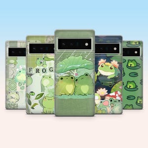 May include: A collection of five phone cases with various green frog designs. The cases feature different illustrations, including frogs with lily pads, hearts, and the word "FROG". The cases have a light green background.