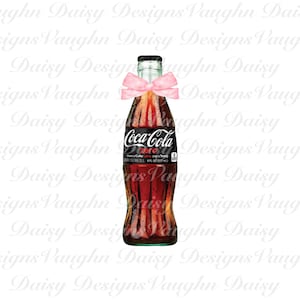 Puede incluir: Una botella de vidrio de Coca-Cola Zero Sugar con una cinta rosa atada alrededor del cuello. La botella está sobre un fondo blanco.