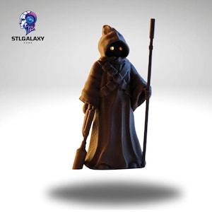 Puede incluir: Una figura impresa en 3D de color marrón de un personaje de Star Wars que lleva una túnica con capucha y sostiene un bastón. El personaje tiene ojos amarillos brillantes.