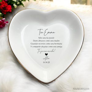 Könnte beinhalten: Weiße herzförmige Keramikschale mit goldenem Rand. Die Schale trägt eine Botschaft in schwarzer Schrift: "Tia Emma Solo una tia puede Darte abrazos como una madre Guardar secretos como una hermana Y compartir alegrias como una amiga Te quiero mucho! Alex 10.30.25"