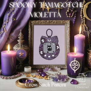 Op de afbeelding: Een kruissteekpatroon met een paarse en zwarte Tamagotchi met een griezelig thema. Het patroon is ingelijst in een gouden lijst en omringd door kaarsen, kristallen en andere decoratieve items. De tekst "Spooky Tamagotchi Violetta" staat bovenaan de afbeelding.